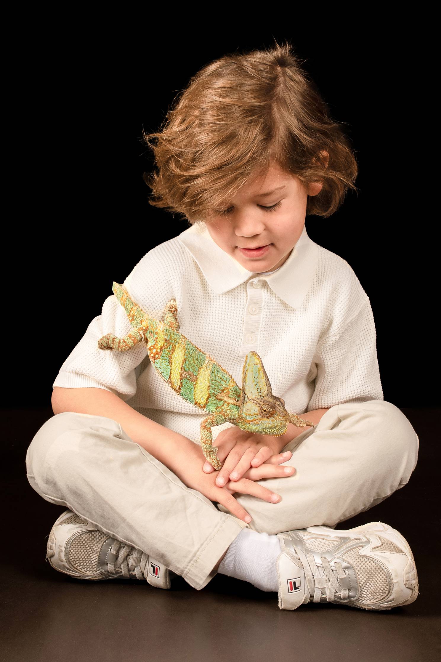 Een jongen met een kameleon op zijn schoot.